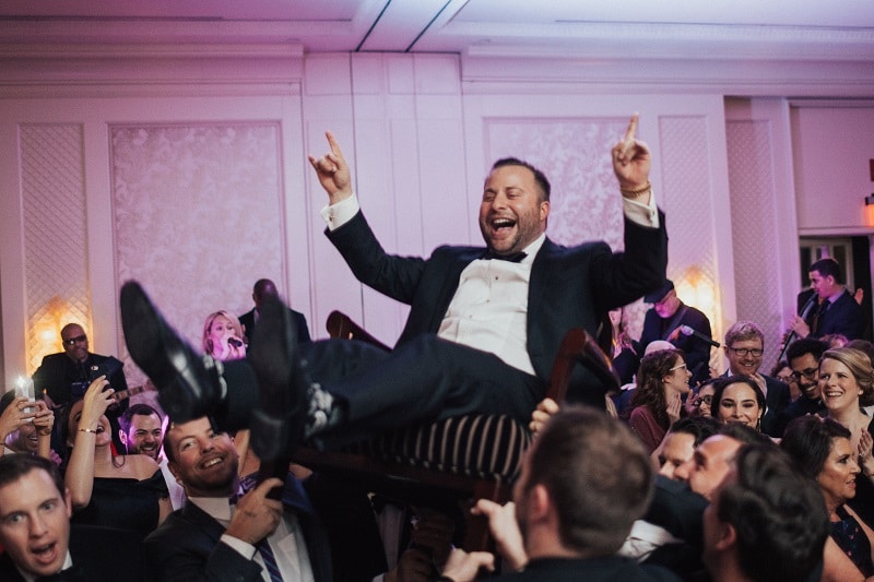 Groom is hoisted on a chair during hora at his wedding