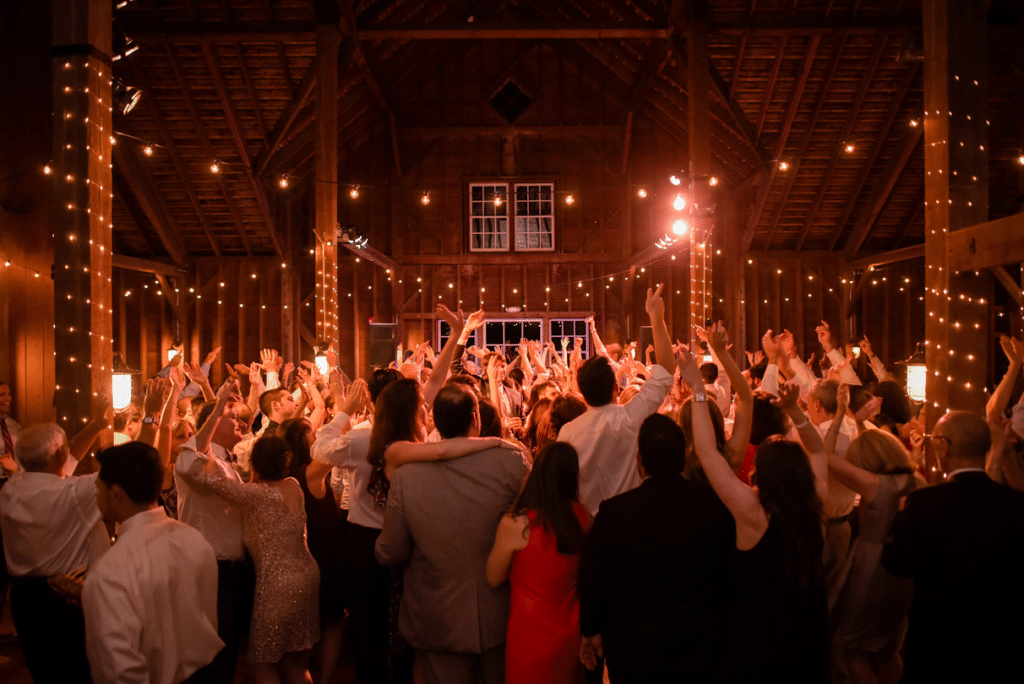Guests dance in barn at wedding reception